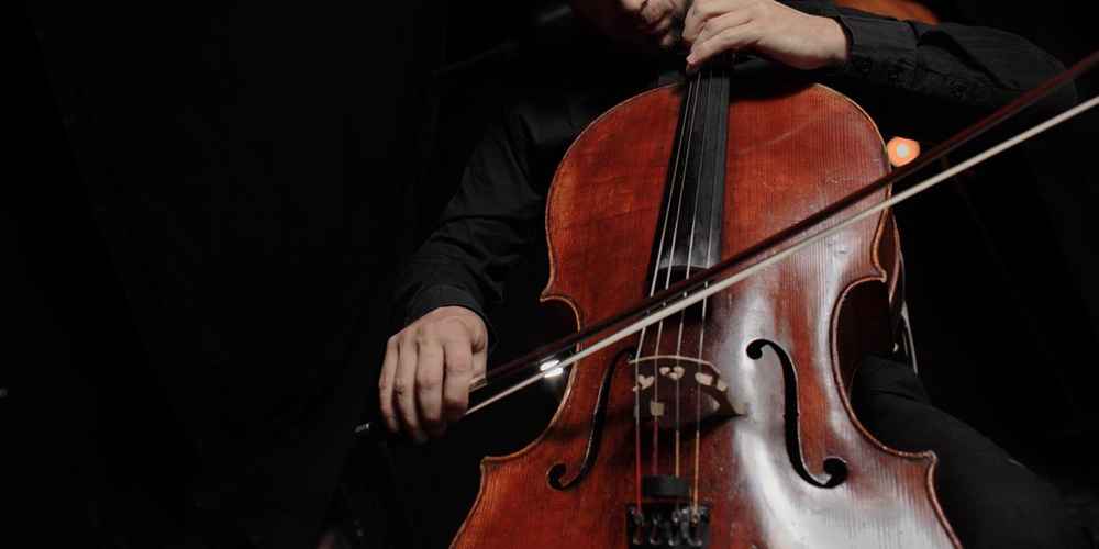 Cello player close up in front of a black background