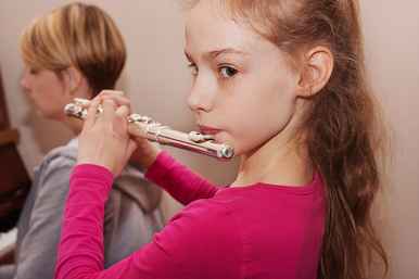 Young girl playing the flute while teacher accompanies