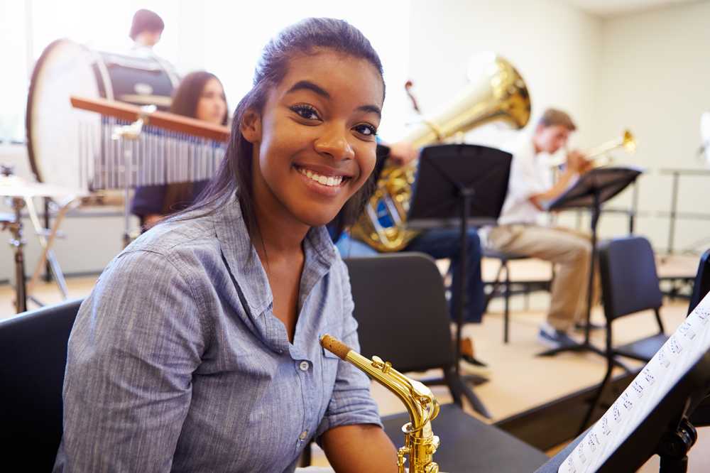 A girl smiling holding the saxophone