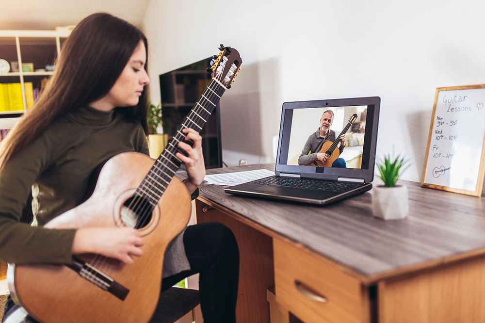 A young woman taking an online guitar lesson