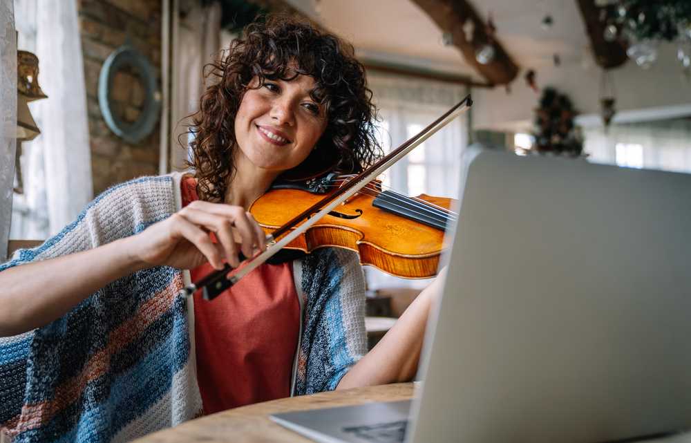 Young woman taking a violin lesson online